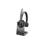 Poly Voyager 4310 M Teams headset with upright boom microphone resting on a black desktop charging stand.
